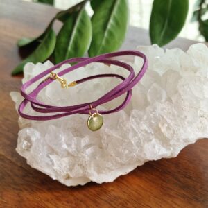 Bracelet triple tour en faux daim mauve, décoré d’une pastille ronde plaquée flash or 18K. Présenté sur fond neutre. Disponible en 15 coloris élégants.