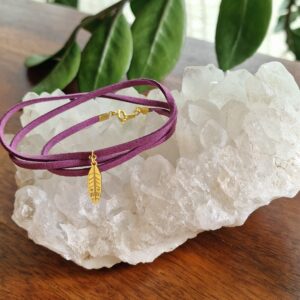 Bracelet triple en faux daim mauve avec fermoir et breloque Plume dorée en acier inoxydable 316L plaqué flash 18K, présenté sur fond clair. Ce modèle raffiné est disponible en 15 coloris pour varier les styles.