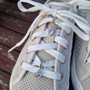 Bijou “Anneau & Strass” monté sur une basket Mustang beige en toile. Pendentif losange arrondi orné en son centre d’un strass en verre blanc, fixé au lacet à l’aide d’un anneau en métal argenté.