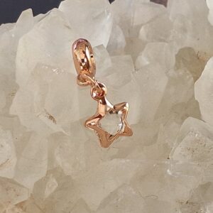 Bijou de basket en forme d’étoile rose entourant un strass blanc brillant, fixé sur une perle en alliage rose, photographié posé sur un druzy de cristal de roche scintillant.